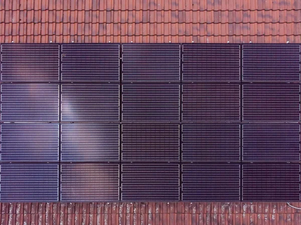 タイル張りの屋根の上に設置された長方形の形状の黒い太陽電池パネル クリーンエネルギー — ストック写真