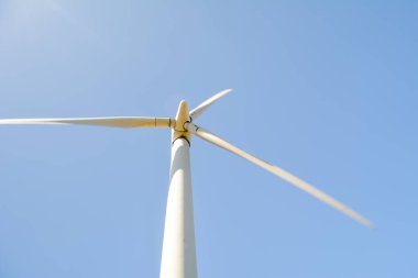 Yenilenebilir ve düşük karbon enerjisi üreten rüzgar türbininin dönen bıçaklarının yakın ve düşük açılı görüntüsü