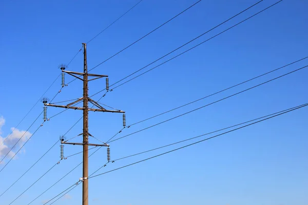 Napájecí tyč a elektrické vedení proti modré obloze — Stock fotografie