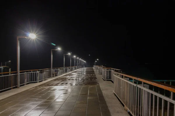 Night scene after rain is a seaside town. Bridge at the port of Pomorie resort near Bourgas, Black Sea,Bulgaria.