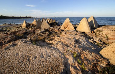 Seascape. Deniz Feneri ve Shabla Köprüsü'nün arka planına karşı kayalar ve beton piramitler. Kuzey Karadeniz Kıyısı, Bulgaristan.