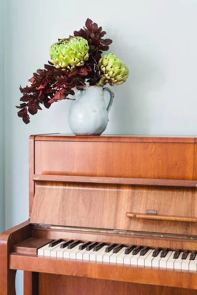Rustikale Vase mit Artischockenblume auf Klavier — Stockfoto