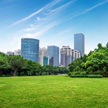 Mali alanının yanındaki çim, yüksek binalar ve ağaçlar. Nanning, Çin.