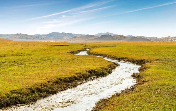 Beautiful grasslands, mountains and meandering rivers are in the distance.