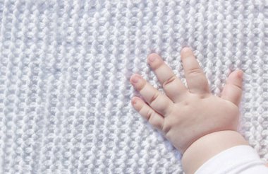 Yeni doğmuş bebek eli, açık avuç içi battaniyede.