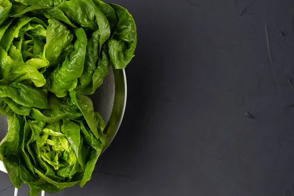 Siyah arka planda metal kevgir salatası. Sağlıklı beslenme.