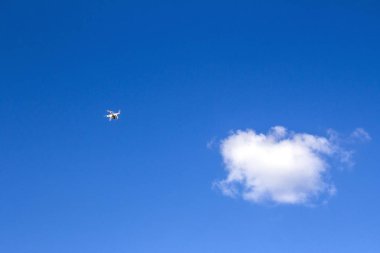 Flying drone in the sky against a TV tower and clouds