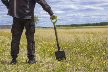 Bakire arazi ortasında duran bir alanı çıkarmak bir düşünceli adam, bir kürek ile