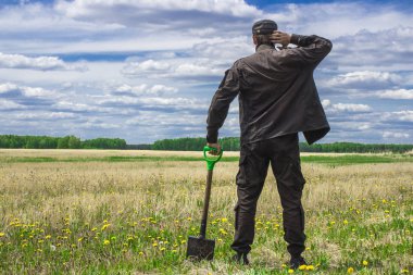 Bakire arazi ortasında duran bir alanı çıkarmak bir düşünceli adam, bir kürek ile