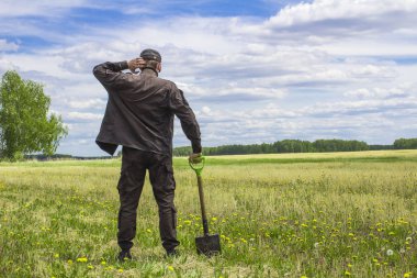 Bakire arazi ortasında duran bir alanı çıkarmak bir düşünceli adam, bir kürek ile