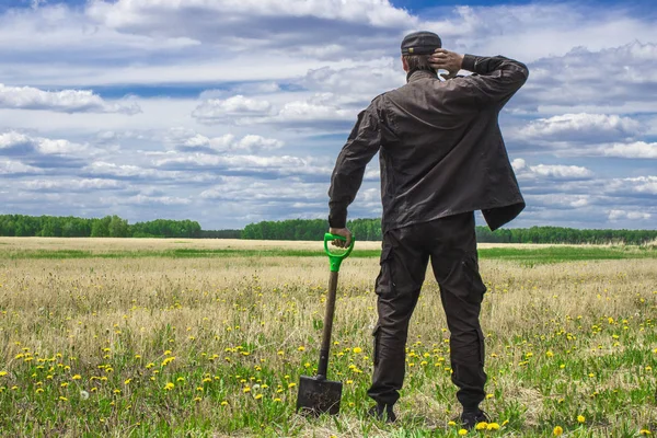 Bakire arazi ortasında duran bir alanı çıkarmak bir düşünceli adam, bir kürek ile