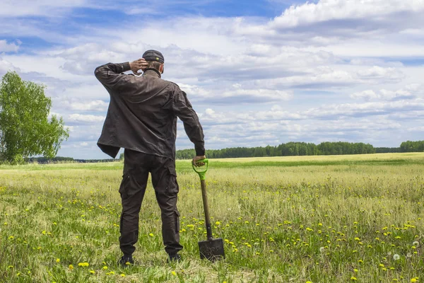 Bakire arazi ortasında duran bir alanı çıkarmak bir düşünceli adam, bir kürek ile