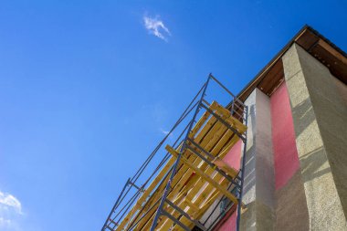 mavi bir gökyüzü altında çalışan iskele üzerinde inşaat işçisi siluet