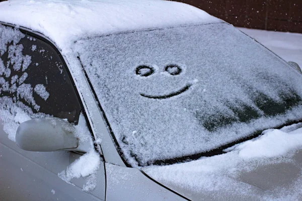 the sad and the happy smile on the snowy windshield of a car