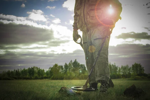 man on a treasure hunt with a metal detector in the woods on the field