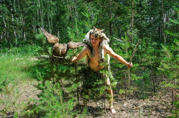 primitive man in the forest hunting with sitting on the arm of an eagle and a lynx skin