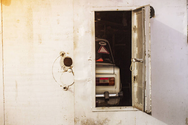 старый автомобиль за открытыми дверями железного гаража
