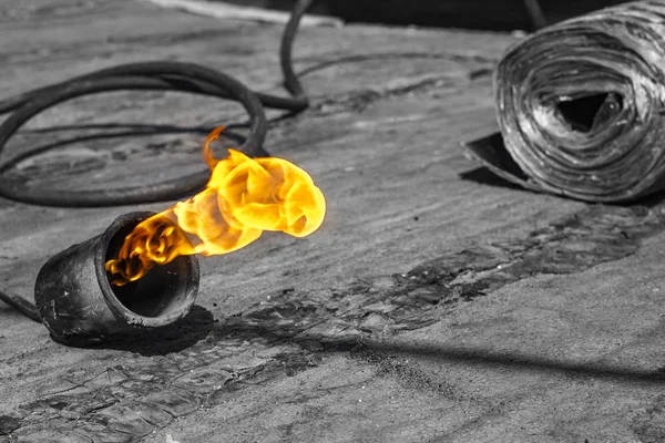 Gas burner with fire and roll of roofing material on blurred bac — Stock Photo, Image