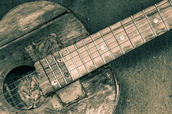 Old guitar on concrete wall background with blurred front and ba — Stock Photo, Image