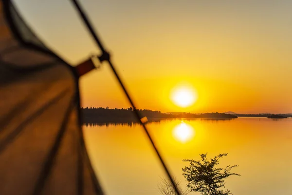 Arc tent blurred in the foreground of a sunset and a lake in the — Stock Photo, Image