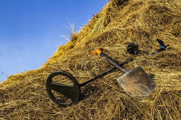 metal detector and sapper shovel on a haystack in an open field
