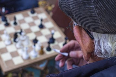 İki yaşlı bilge ve sigara içen adam sonbaharda eski satranç oynuyorlar.