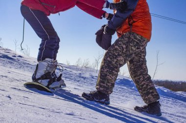 Çocuklar açık bir günde dağ yamacında snowboard yapmayı öğrenirler.