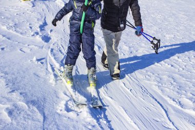 Çocuklar açık bir günde dağ yamacında snowboard yapmayı öğrenirler.
