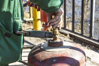 Çalışan adam gaz silindirli propanı kontrol ediyor.