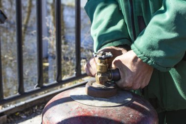 Çalışan adam gaz silindirli propanı kontrol ediyor.