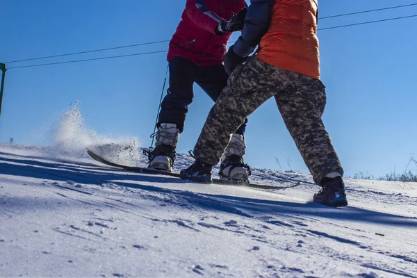 Děti se naučí snowboard na horském úbočí za jasného dne — Stock fotografie