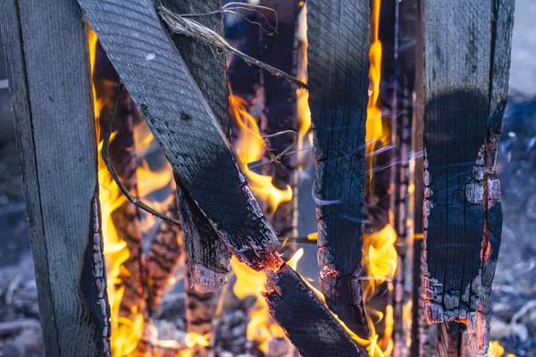 Verbrannter Zaun in Großaufnahme auf der Asche eines großen Feuers, auf einem verschwommenen — Stockfoto