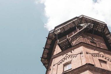 Bulutlu mavi gökyüzünün arka planında antik tuğlalardan yapılmış eski su kulesi.