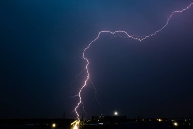 Gece gök gürültülü bir fırtınada, karanlık gökyüzüne karşı, bir yangına neden olan bir ormanda, yağmurlu bir fırtınada güzel bir yıldırım.
