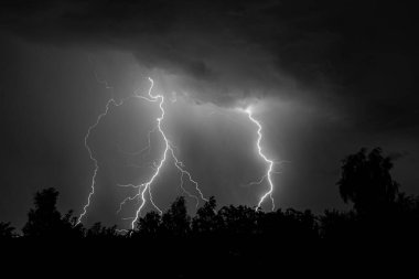 Gece gök gürültülü bir fırtınada, karanlık gökyüzüne karşı, bir yangına neden olan bir ormanda, yağmurlu bir fırtınada güzel bir yıldırım.