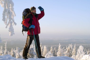 Gezgin adam dağın zirvesinde kış soğuk scener üzerinde ayakta kol altından mesafe bakarak bir sırt çantası ile