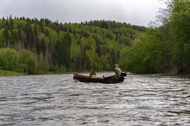 Bulutlu bir günde vahşi Nehri boyunca bir geleneksel ahşap düz oturaklı tekne tekne motor ile iki kişi float
