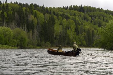 Bulutlu bir günde vahşi Nehri boyunca bir geleneksel ahşap düz oturaklı tekne tekne motor ile iki kişi float