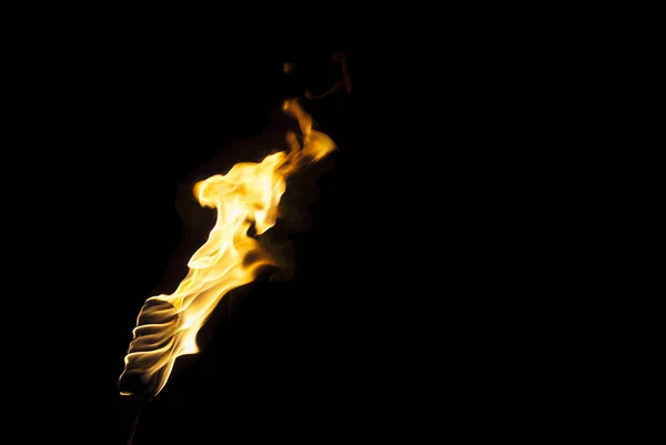 黒い背景の上の暗闇の中でたいまつの炎火だけが見える — ストック写真