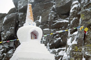 KACHKANAR, RUSSIA - JANUARY 09, 2018: Buddhist stupa in the monastery of Shad Tchup Ling - the only Buddhist monastery in the Ural Mountains - against the background of a blurred snow-covered rock clipart