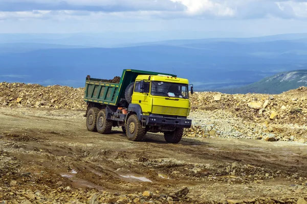 loaded dump truck rides on the mountain road under construction