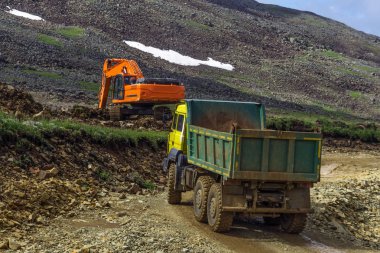 Dağlık bir alanda, bir ekskavatör ve bir damper bir yol inşaat çalışmaları sırasında döşeme