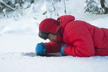 bir adam kış nehir buz üzerinde yatıyor ve temizlenen kar komplo buza bakar