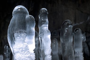 group of transparent ice stalagmites in a cave closeup on a dark background clipart