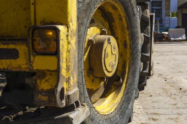 bir şehir onarım çalışmaları sırasında sokak üzerinde büyük bir tekerlek ile yüklü ağır yıpranmış traktör parçası monte