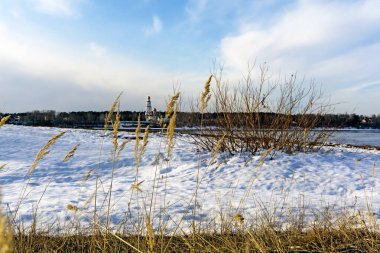 güneşli bir günde kadar sahilde bir Ortodoks Kilisesi ile geçen yılki çim bir bulanık bahar nehir arka planı kuru altın spikelets manzara
