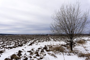 kar ile mesafe ve ufukta bir şehir bir köyde erken baharda erime ile sürülmüş alan