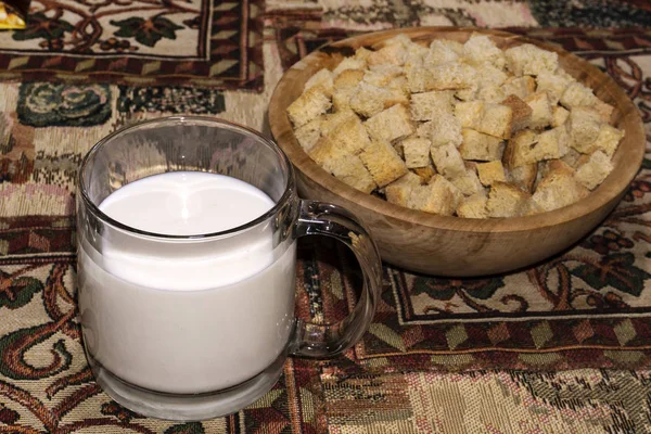 mug with a sour milk drink and a wooden bowl with rusks squares