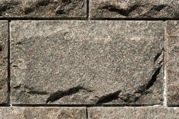 rough granite rectangular block in the composition of masonry wal