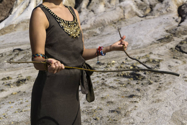 женщина ищет воду в пустынной местности методом даунсинга; видны только ее туловище и руки
